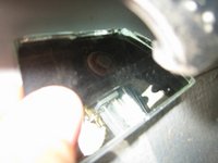 Mit einem Spiegel auf die Rückseite der Fensteraufnahme geschaut. Man erkennt wieder die messingfarbene Schraube für den Anschlagpuffer und auf der Rückseite grob die Schraube mit Sprengring, welche durch die Scheibenaufnahme geht.